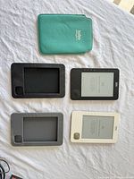 All items laid out: two eReaders, two covers, green sleeve