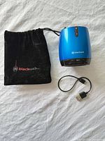 Speaker, pouch, and charging cable displayed together