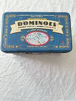 Top of blue Schylling dominoes tin showing product name and features
