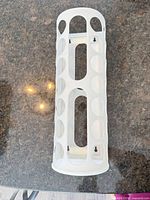 IKEA white plastic cylindrical bag dispenser showing oval openings and wall-mount slots