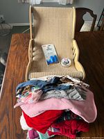 All items in lot: small pet chair, stack of dog clothes, finger toothbrush pack, paw balm tin
