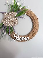Full view of jute twine wreath with polka-dot burlap bow, faux lavender, white buds and "Home" sign