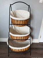 full view of black metal rack holding three wicker baskets with fabric liners