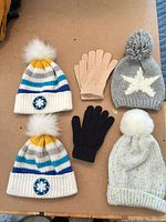 Overview of 4 beanies and 2 glove pairs laid out