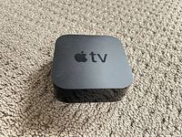 Top view of Apple TV 4K box showing logo and surface wear