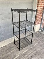 Full view of black four-shelf wire unit standing upright