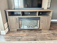 Front view of TV stand showing fireplace insert, open AV shelves, side cabinets, top surface