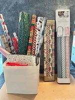 Overall lot: storage cube filled with multiple rolls of Christmas wrapping paper; boxed sets of wrap rolls at side
