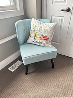Front view of accent chair with pillow displaying upholstery color and pillow design