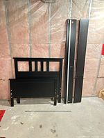 Headboard, footboard and side rails standing against wall