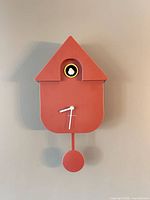 Full front view of Karlsson red cuckoo wall clock showing pendulum