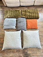 All five pillows and two olive throws displayed on floor