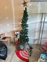 Assembled slim tree with star topper, tree skirt, foot pedal visible