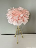 Full view of pink feather shade lamp on gold tripod base