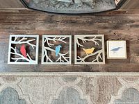 All four bird wall art pieces lined up on floor