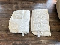 Two folded white twin duvets laid flat on floor
