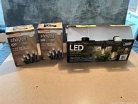 Two Sylvania mini light boxes and one Feit LED string light box displayed together