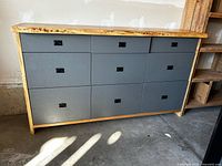 Front view of grey credenza with live-edge maple top, nine drawers