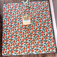 Blanket fully opened showing orange fruit pattern and integrated cooler bag
