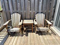 Two wooden Adirondack chairs and side table on deck