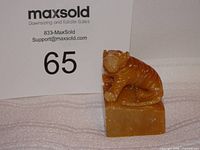 Front view of carved stone tiger on base with scale card