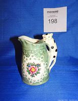 Front view showing cat handle, floral motif and overall glazing