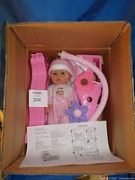 Entire set inside original shipping box, showing doll, seat components, mobile arm, instruction sheet