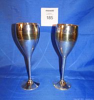 Front view of the two silver and gold tone goblets standing upright