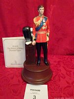 Front view of Prince Charles figurine on wooden plinth with certificate behind