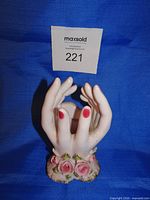 Front view of ceramic hands vase showing roses and open top