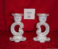 Front view of both porcelain candlesticks showing rose decals and gold trim