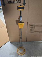 Full view of metal detector standing upright showing search coil, shaft and control housing
