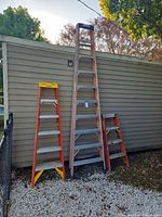 Three Werner fiberglass step ladders leaning against building; shows relative sizes