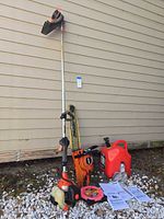 Overall view of Echo string trimmer hung on wall, Echo chainsaw with bar, bar scabbard, fuel can, line spool, manuals