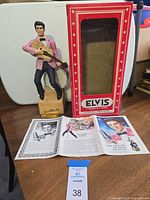Full view of figurine, guitar, snare drum, wood base, box, COA card, pamphlet