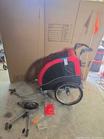Trailer/stroller with rear wheel, tow arm, front wheel, tools, manual and flag displayed