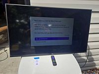 Front view of TCL 43" Roku TV on table displaying setup screen with remote visible
