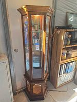 Full view of curio cabinet showing wood finish, glass panels, base and lighting