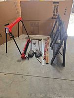 Group view of Bauer stand pieces, plastic sawhorses, levels, squares, knee pads, crowbar and other hand tools