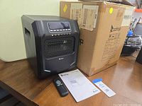 Heater front angled view next to original box, showing remote and manual