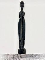 Front view of carved wooden African female figure holding pestle