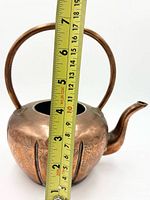 side view showing full kettle, arched handle, curved spout, no lid