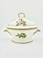 Front view of porcelain soup tureen showing lid, handles, floral painting and gilded trim