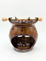 front view showing opening, cutouts, glaze, wooden rod and bowl