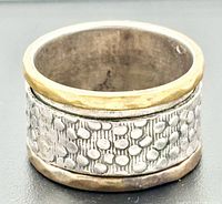 Wide sterling silver band with brass spinner edge visible