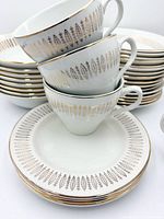 Stacked teacups on saucer showing feather motif and gold rim