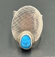 Front view showing textured oval face and turquoise cabochon