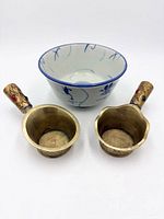 front view of two brass irons and porcelain bowl