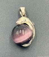 Front view of pendant showing dolphin shape and purple orb