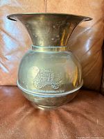 Full view of brass spittoon front side showing logo and shape